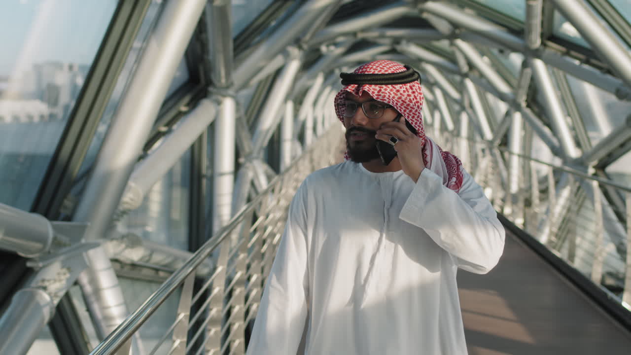 Sheikh Talking On Phone During Walk Along Indoor Glass Bridge