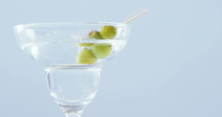 Bastoncino d'oliva che cade nel bicchiere da cocktail