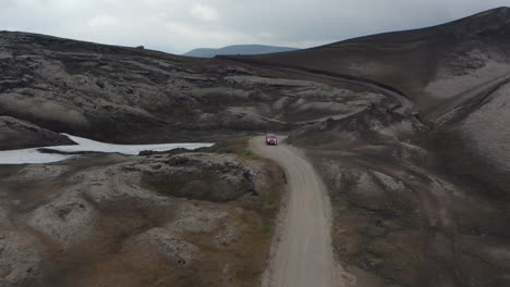 Aerial-view-4x4-car-driving-on-winding-road-discovering-wilderness-of-Iceland-highlands.-Drone-view-offroad-vehicle-traveling-dirt-road-in-icelandic-countryside.-Adventure-and-discovering