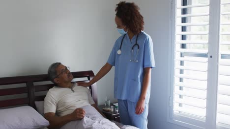 hombre de raza mixta sénior con una doctora que lleva una máscara facial en casa de visita