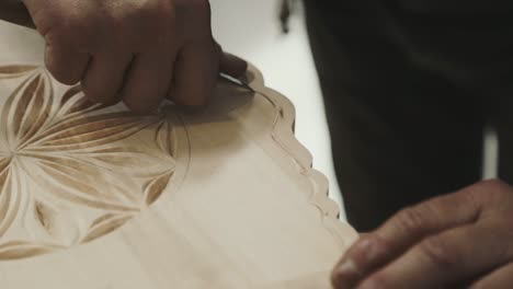 a man engraving his wooden cradle with more precise hand technique