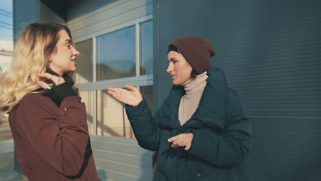 female friends talking and laughing while walking down the street