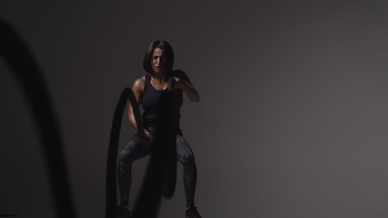 Studio Shot Of Mature Woman Wearing Gym Fitness Clothing Doing Cardio Exercise With Battle Ropes 2