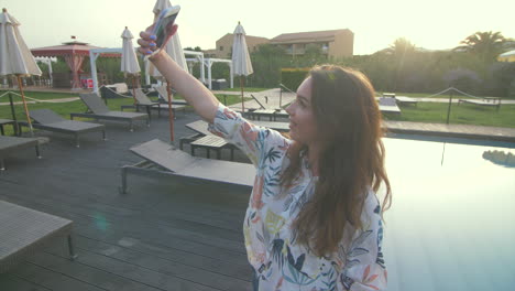 una mujer se toma una selfie junto a la piscina.