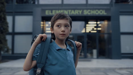 cute teen boy standing at school building close up. guy ready start studying.