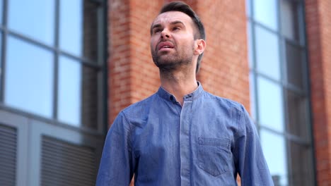 pensive serious man standing outside office building