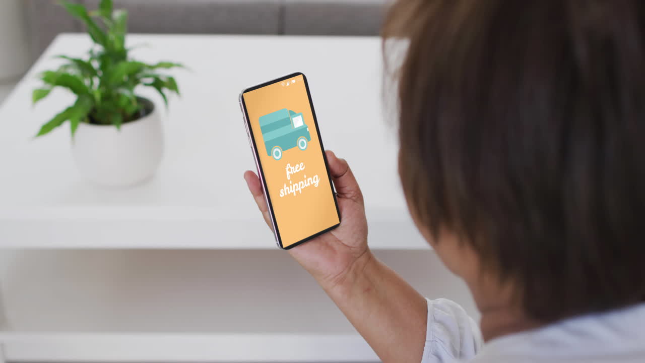 mujer biracial usando teléfono inteligente en casa para comprar en línea, cámara lenta