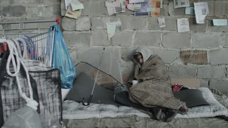 a person experiencing homelessness wrapped in a blanket against a wall