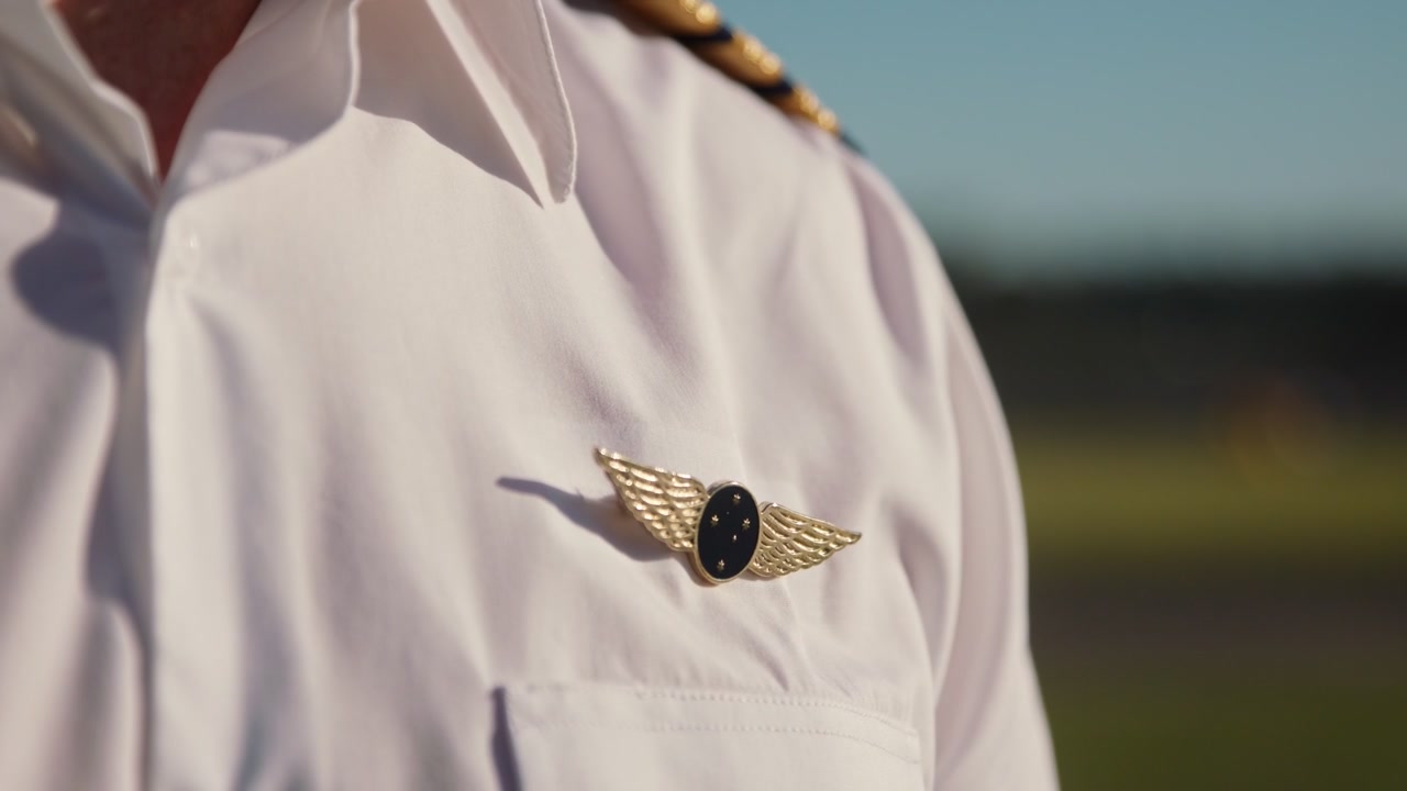 Un pilota nella sua uniforme, quando si gira c'è un leggero riflesso sul suo distintivo