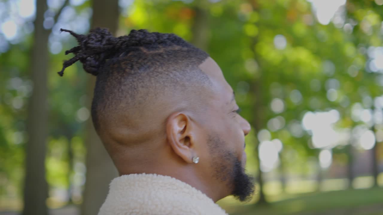 un hombre negro caminando felizmente con su perro a través de un parque en un soleado día de otoño