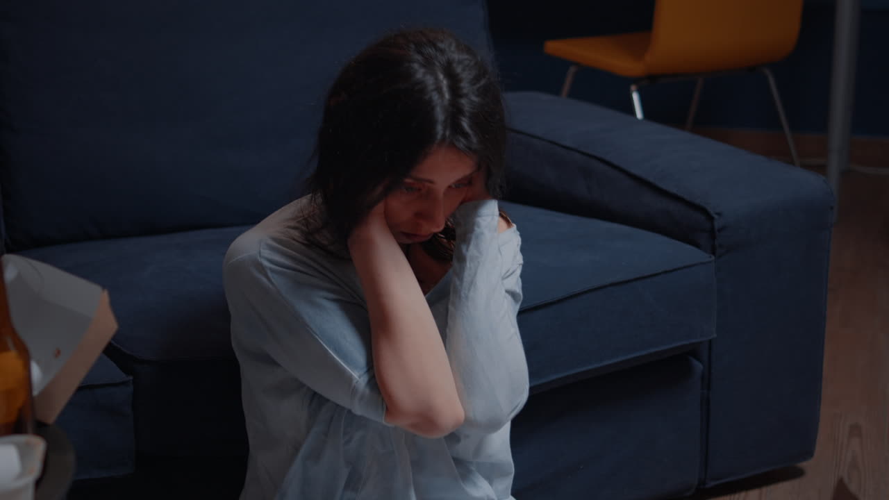 Sad hopeless young woman sitting alone at home feeling desperate