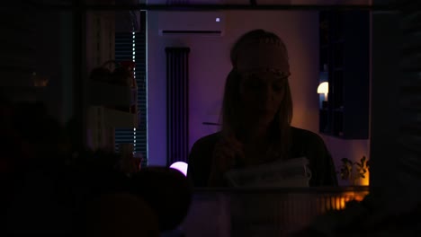 mujer comiendo un bocadillo nocturno del refrigerador