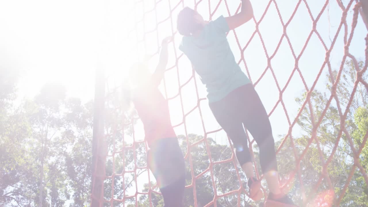 장애물 코스 중 등반 네트워크에서 여성을 돕는 여성 트레이너