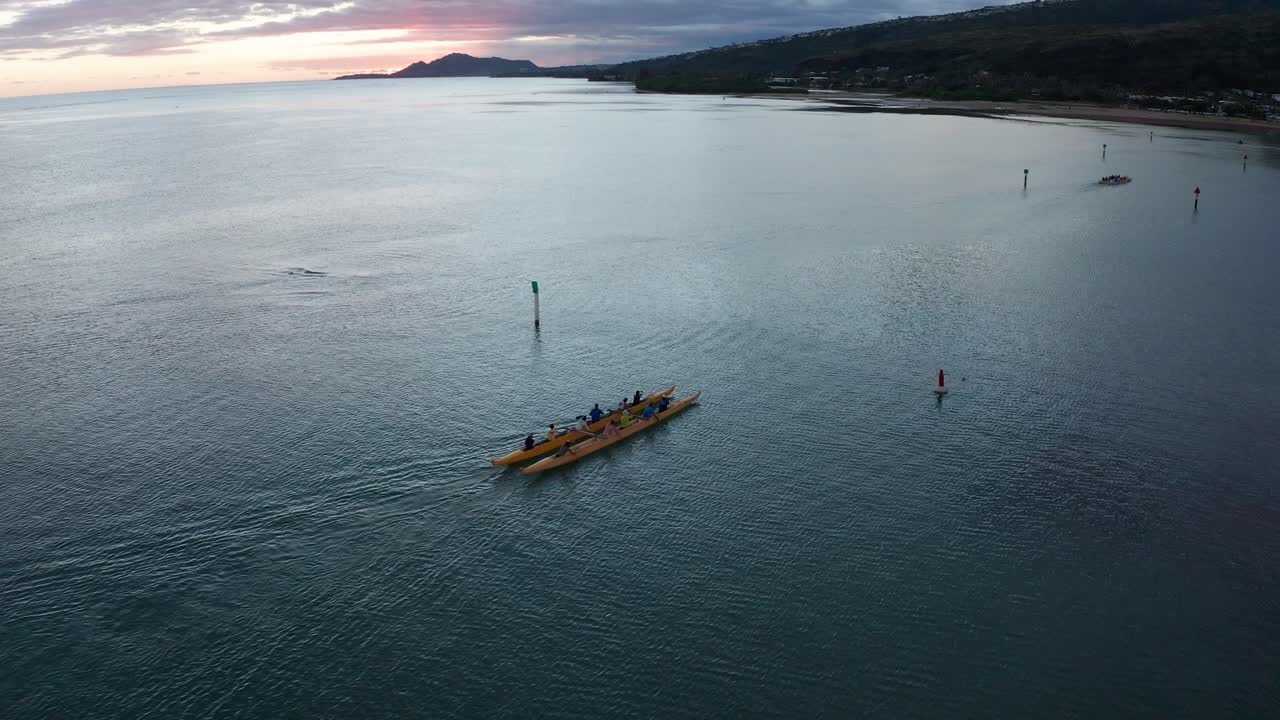 Descending aerial shot of an outrigger canoe rowing on the ocean in O'ahu, Hawaii