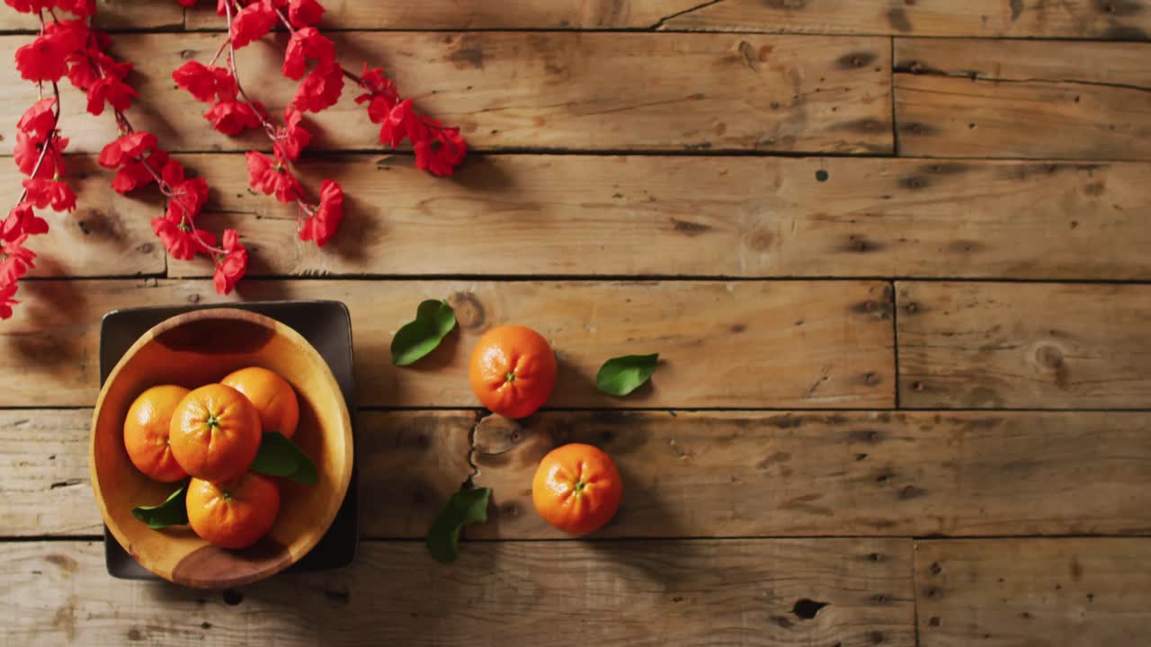video de naranjas y flores rojas sobre fondo de madera