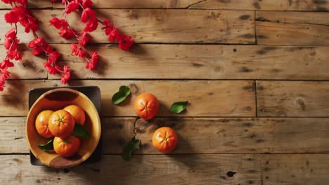 video of oranges and red flowers on wooden background