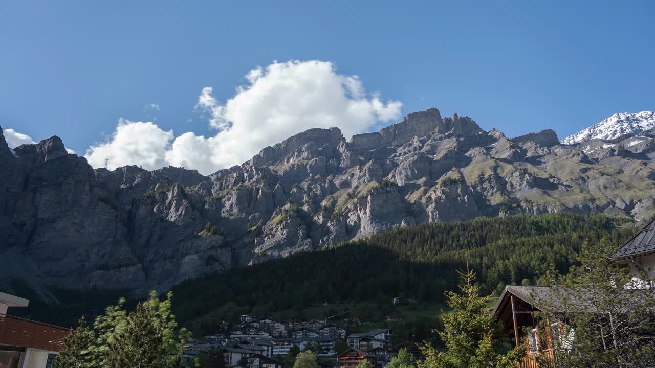 Time-lapse in the Swiss Alps in Valais, Leukerbad. The small village in the mountainous landscape surrounded by forests and mountain ranges. Clouds drift over the mountain peaks in summer.