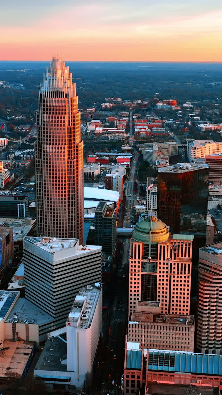 Splendida architettura del bellissimo centro di una metropoli nella luce rosa del tramonto. Vista dall'alto su Charlotte, Carolina del Nord, USA, con uno straordinario orizzonte sullo sfondo. Video verticale