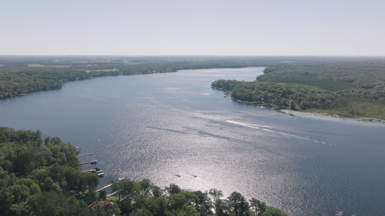 위스콘신 주 하프문 호수 (half moon lake) 의 풍경적인 공중 풍경으로, 은 날에 보트 활동과 숲이 인 해안가를 보여줍니다.