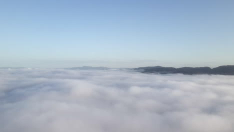 Volando-Sobre-Los-Cielos-Revelando-Un-Cielo-Azul-Y-Cimas-De-Montañas-En-La-Distancia