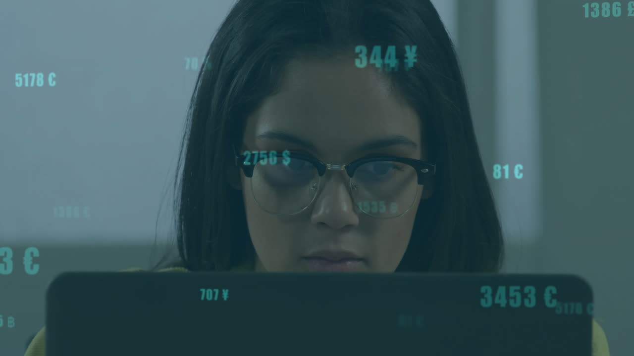 woman using laptop in office, displaying floating finance data, currency symbols overlaying screen