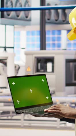 vertical video engineer in smart factory using green screen laptop to analyze iot sensors data