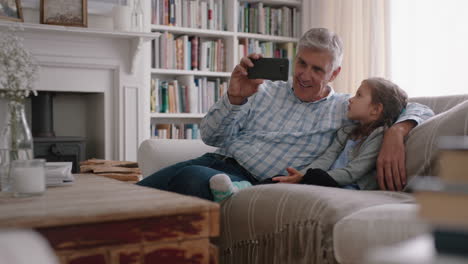 Abuelo-Y-Niño-Teniendo-Video-Chat-Usando-Teléfono-Inteligente-Niña-Compartiendo-Fin-De-Semana-De-Vacaciones-Con-La-Familia-Abuelo-Disfrutando-Charlando-Sobre-Tecnología-Móvil-En-Casa-Con-Nieta