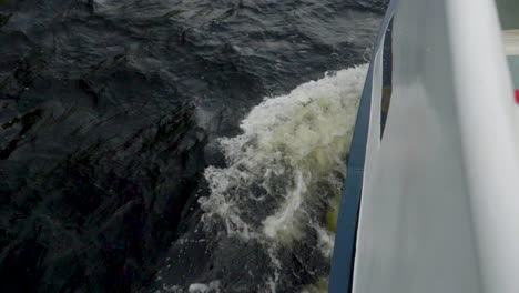 Slow-motion-shot-down-towards-the-bow-of-a-boat-leaving-wake---Milford-Sound-,-New-Zealand