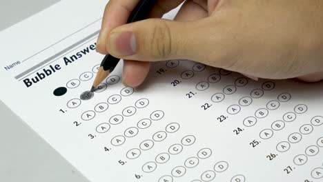 asian student hand doing examination test with standardized test form and answers bubbled.