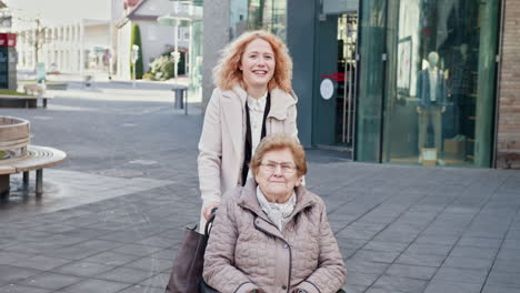 young woman assisting elderly woman in wheelchair