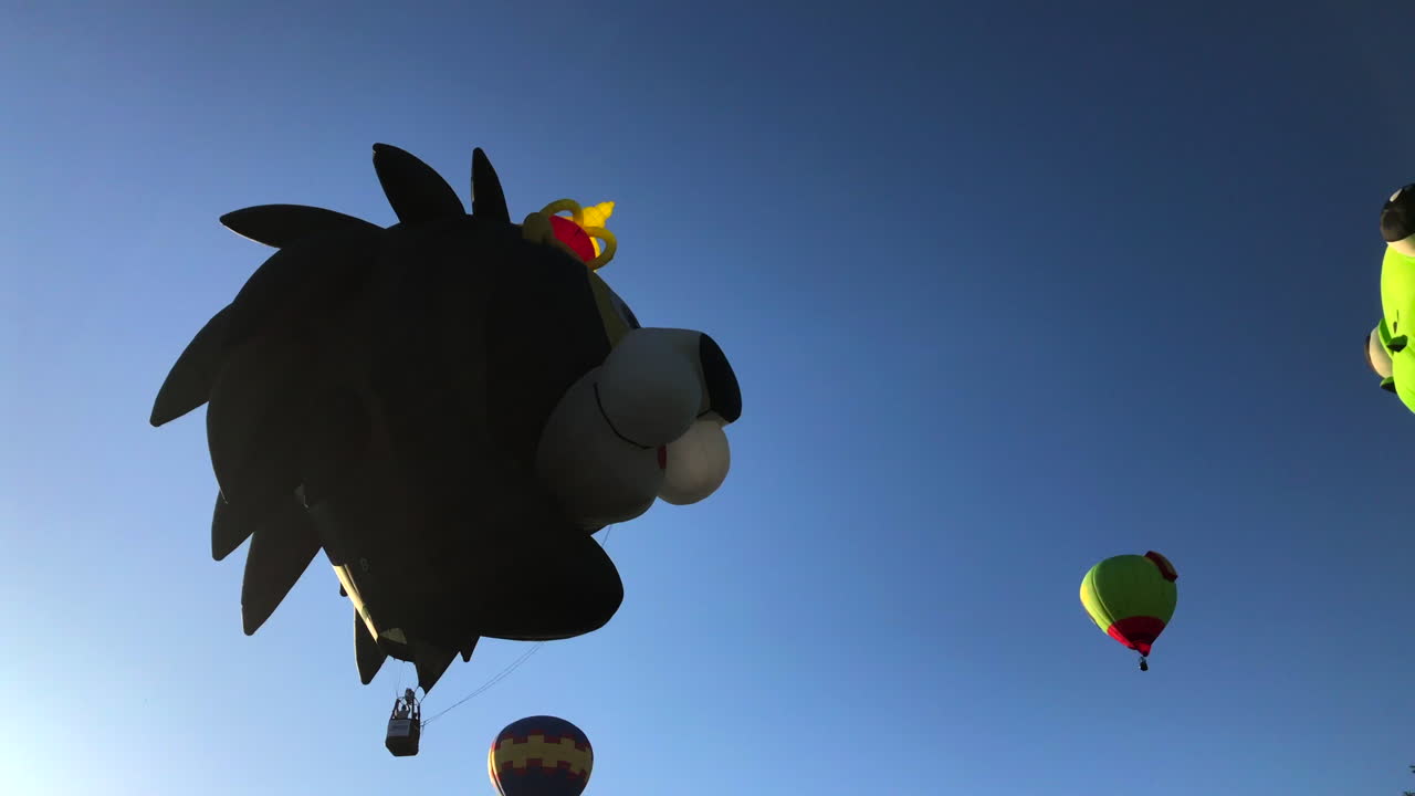 los globos de rana y león se levantan y flotan sobre los árboles