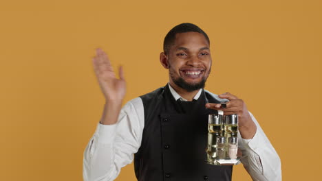 Happy-friendly-waiter-waving-hello-and-welcoming-clients-at-table