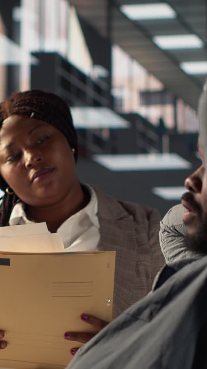 Man Stretching During Work Break While Colleague Discusses Documents
