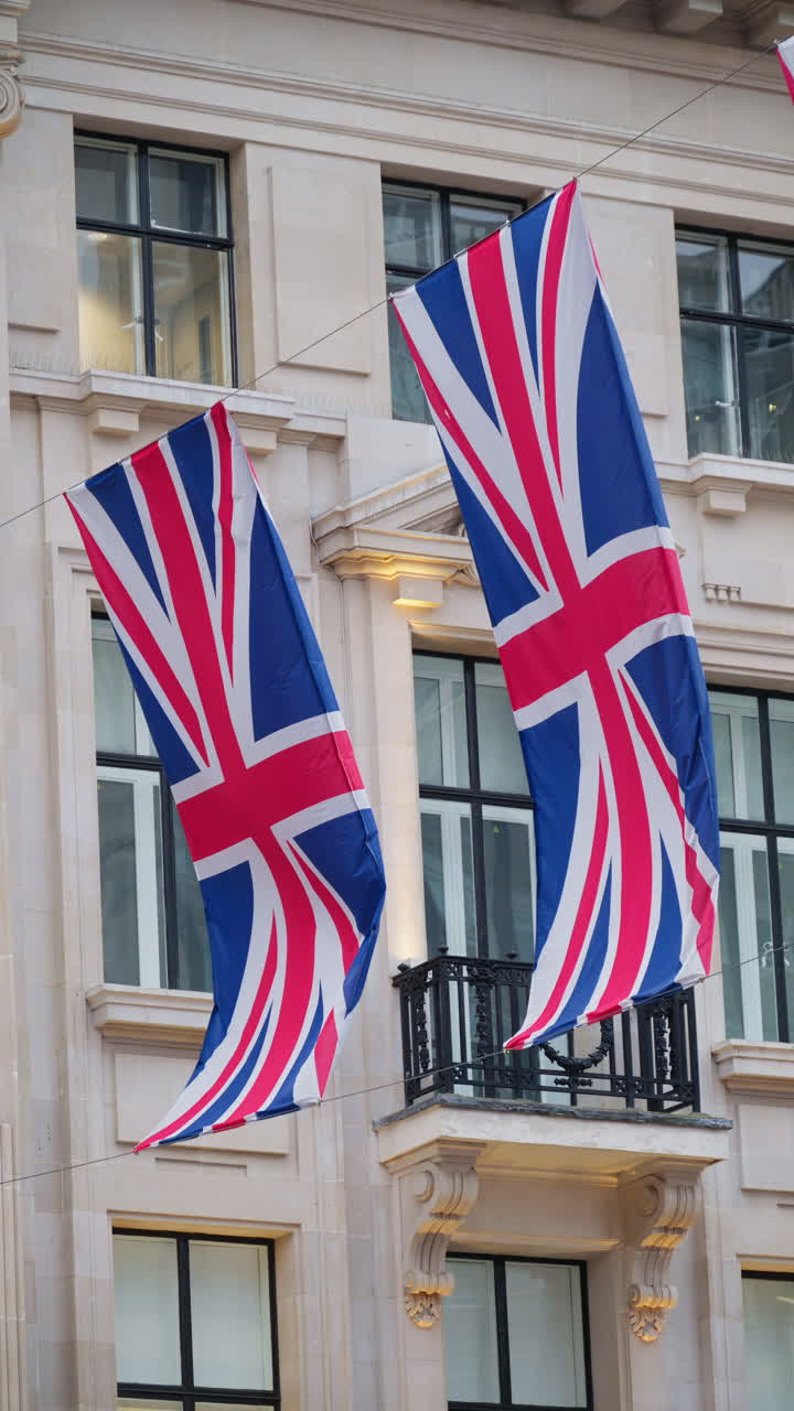 Classic London architecture adorned with waving Union Jack flags. Vertical