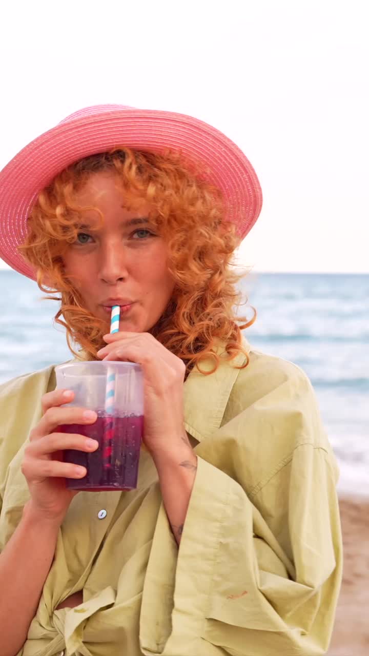 Woman with red hair enjoying a drink on the beach