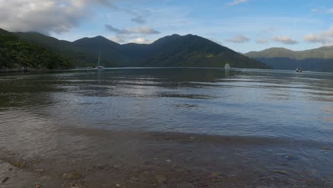 Amplia-Vista-De-La-Hora-Dorada-Desde-Una-Bahía-Aislada:-Aguas-Tranquilas,-Colinas-Y-Un-Barco-Entrante