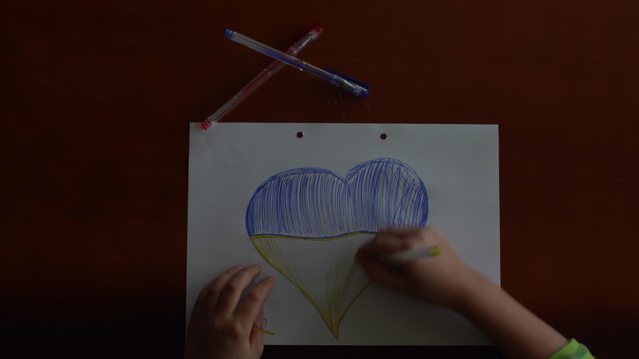 bandera ucraniana y un corazón en color amarillo y azul. el niño dibuja un corazón en la pizarra