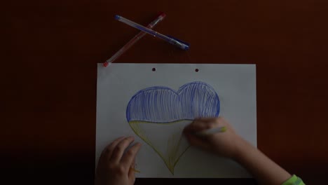 ukrainian flag and a heart in yellow and blue color. child draws a heart on the blackboard