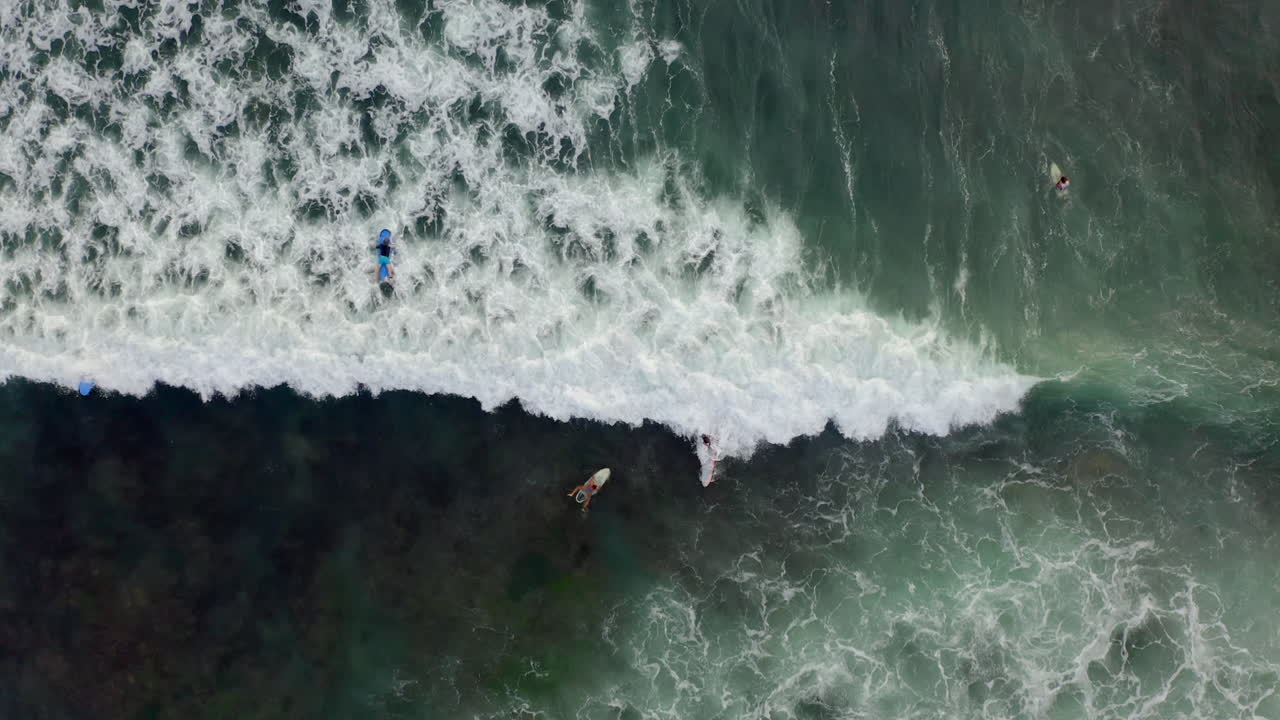 Vista aerea di surfisti che cavalcano le onde dall'alto dell'oceano blu