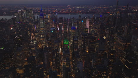 Aerial-evening-footage-of-rows-of-skyscrapers-along-streets-in-midtown.-Cityscape-after-sunset.-Manhattan,-New-York-City,-USA