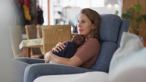 video of caucasian mother sitting in armchair with newborn baby