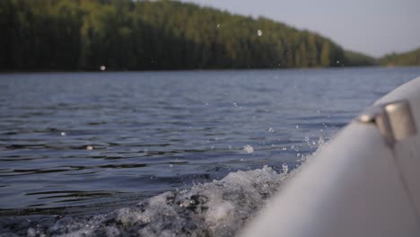 big wave and ripples on a lake while in a boat with sun shining in the background blurry forest moody evening atmoshere