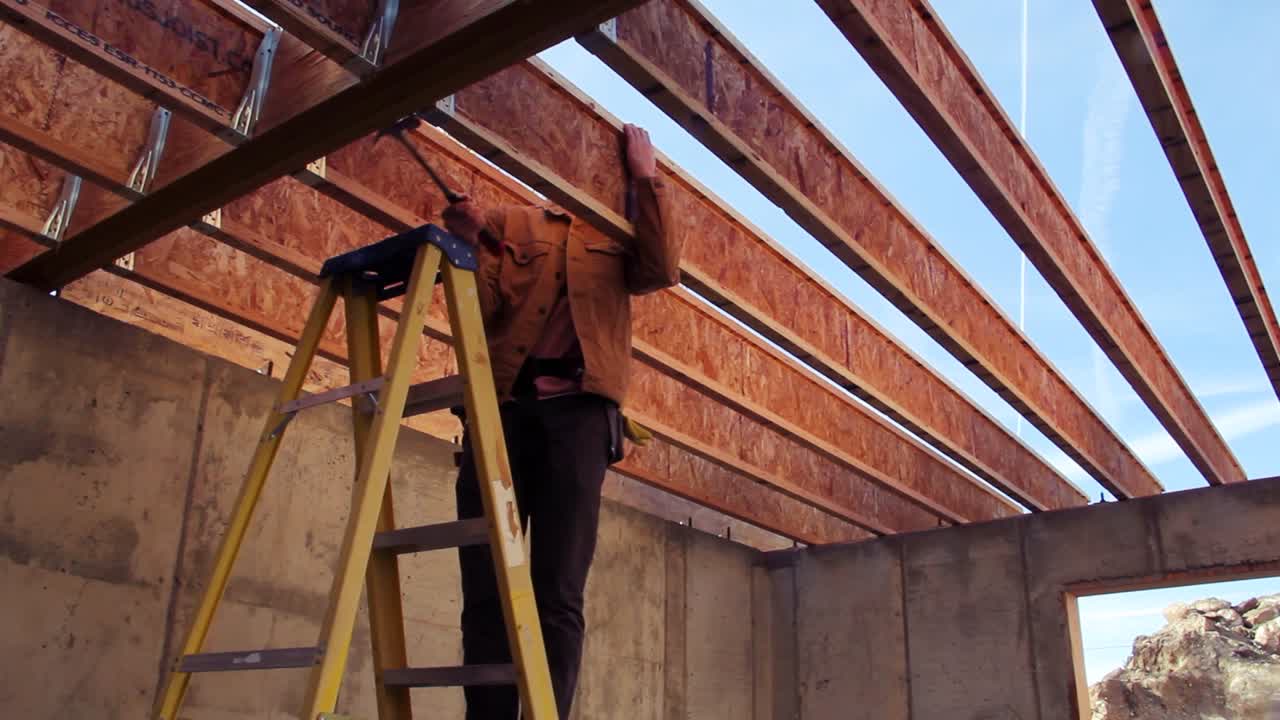 Man hammers a nail into a floor joist