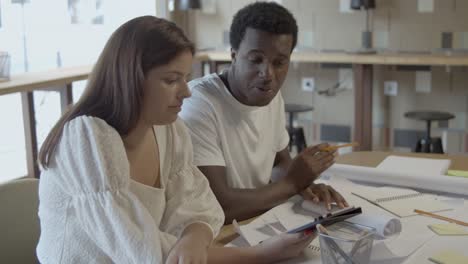 young designers sitting at table with tablet and blueprint