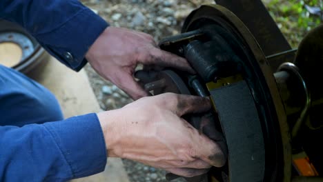 Home-mechanic-adjusts-and-installs-car-parts-on-disc-brake-system,-greasy-hands-at-work