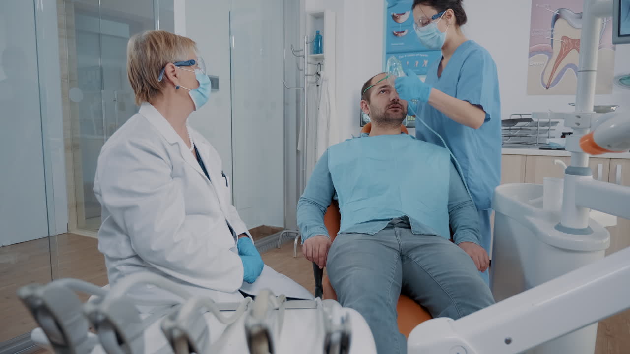 Dentistry assistant putting oxygen mask on face of patient