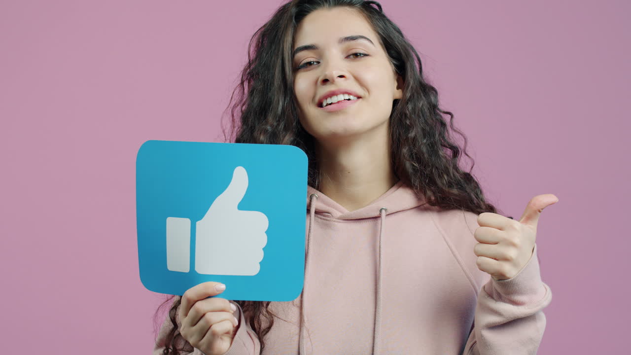 Woman giving a thumbs up and holding a social media like icon.