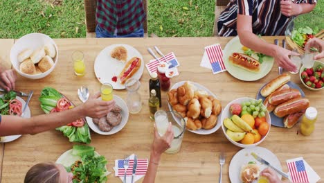 overhead view of caucasian three generation family at table making a toast during meal in garden