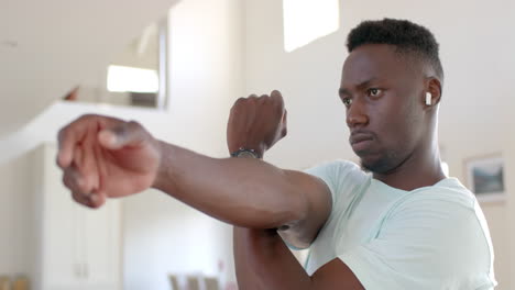 focused african american man stretching in sunny living room, slow motion