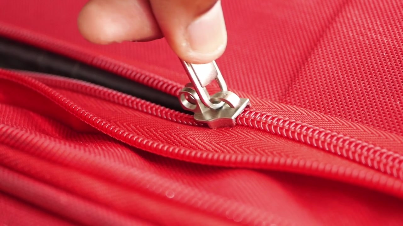 Close-up de uma Mão Fechando um Zíper Vermelho